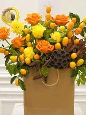 Crimson Sunset Bouquet with orange and yellow roses in a brown gift bag