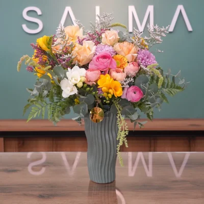 Spring Harmony Vase - A vibrant and cheerful arrangement featuring 100% fresh roses, freesias, and ranunculus in an elegant textured vase. The perfect Spring Harmony Vase to brighten anyone's day in Amman!